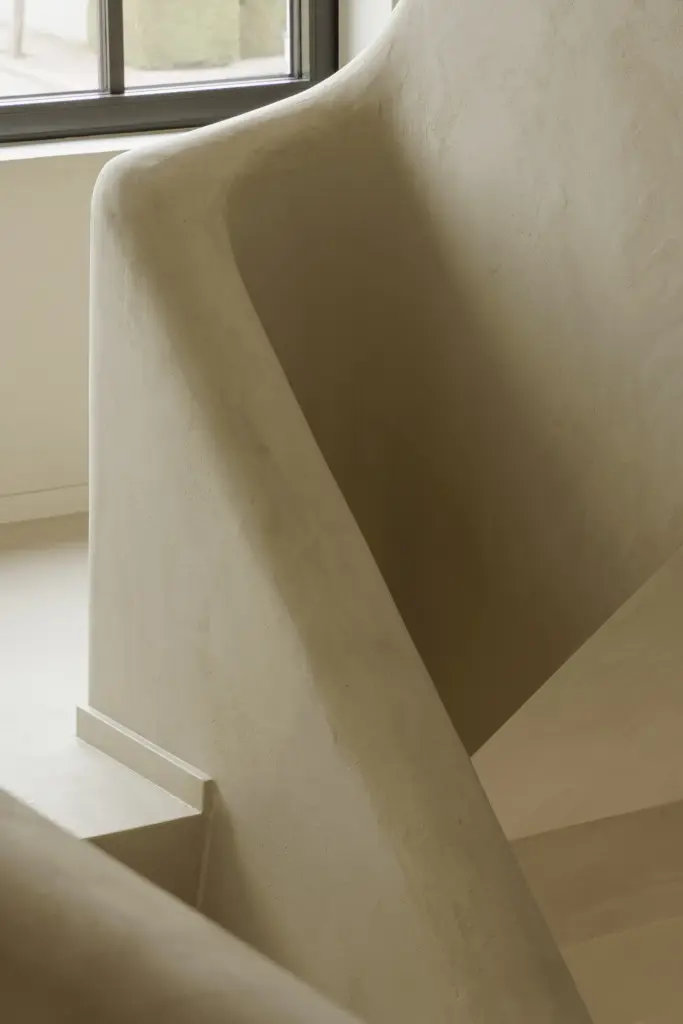 Gepleisterde trapleuning met een zwart raam op het trapportaal, Villarenovatie in Knokke, interieur Laura Calleeuw