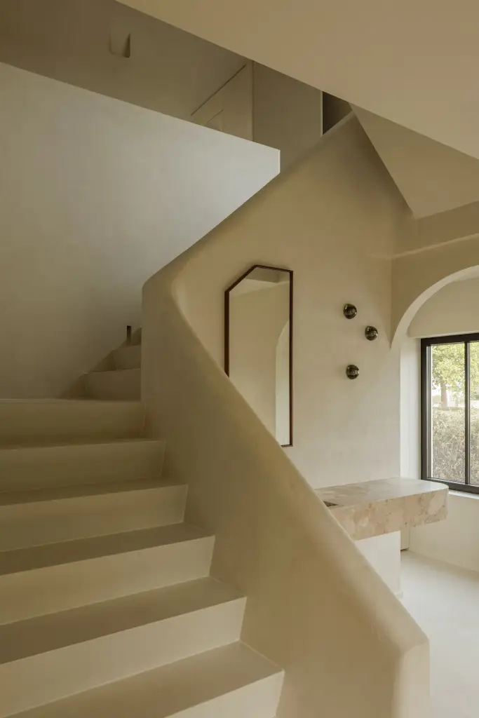 Gebogen gepleisterde trapleuning met een wastafel en spiegel op het overloopje, Villarenovatie in Knokke, interieur Laura Calleeuw
