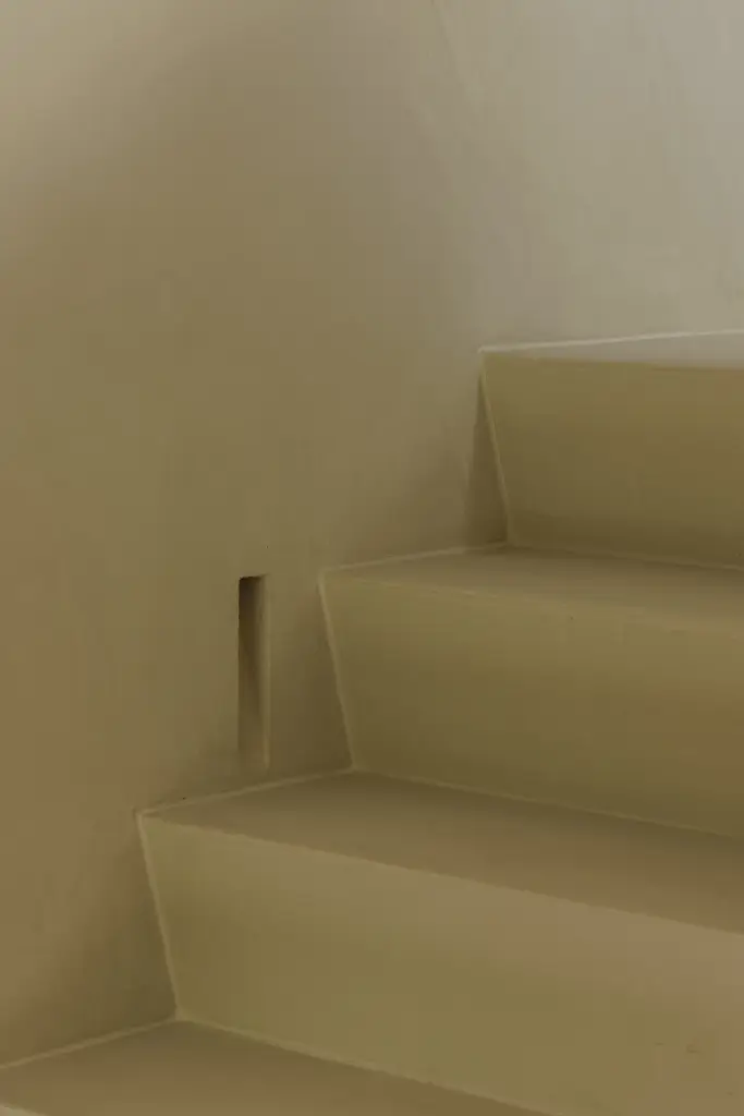 Gepleisterde trap met een ingewerkt lichtpunt in de zijwand, Villarenovatie in Knokke, interieur Laura Calleeuw