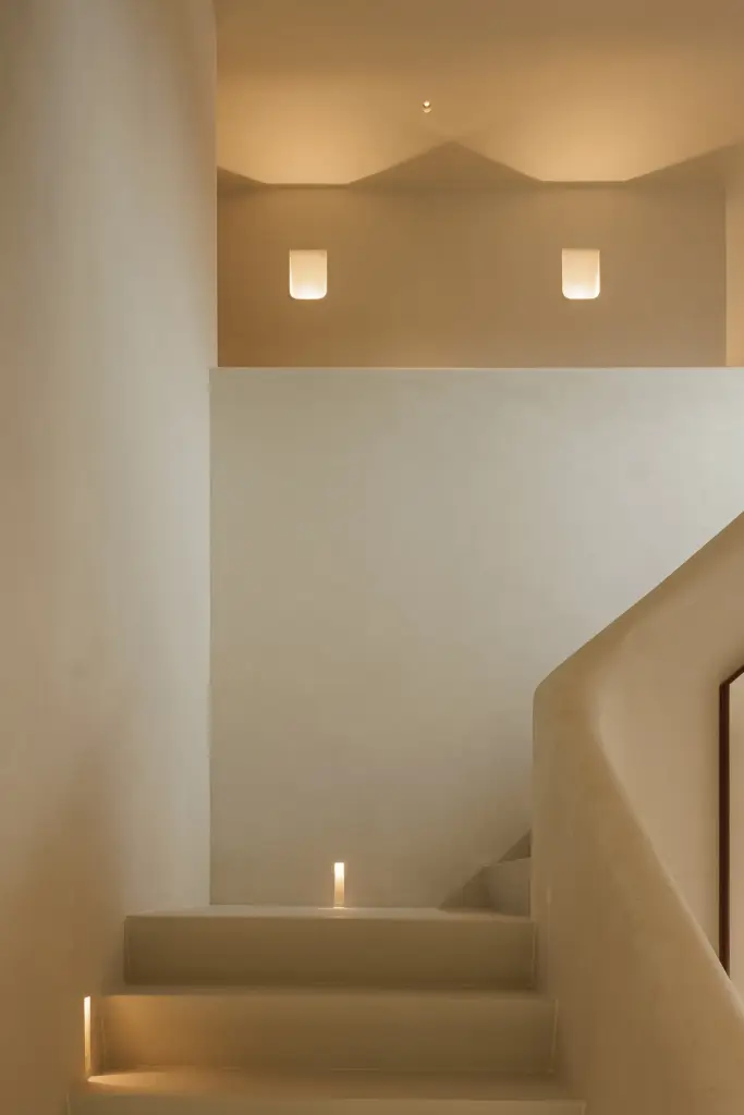 Trap met ingewerkte verlichting in de treden en twee wandlampen in de nis, Villarenovatie in Knokke, interieur Laura Calleeuw