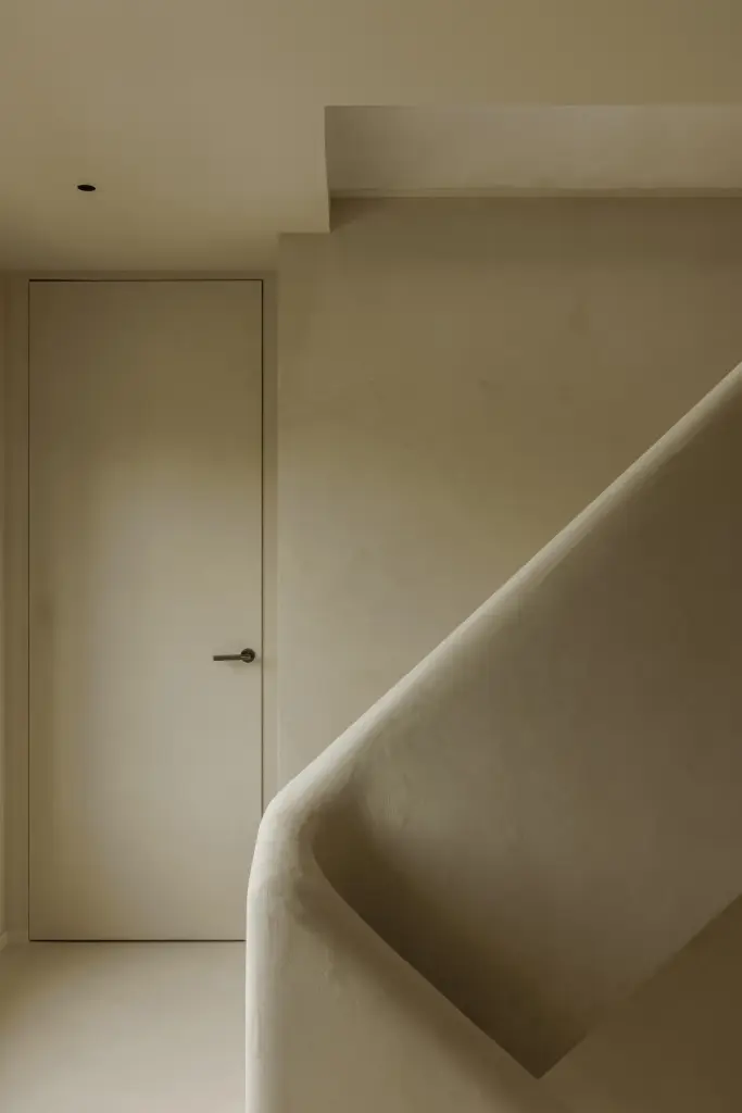 Trappenhuis met gepleisterde trap en vlakke deur, Villarenovatie in Knokke, interieur Laura Calleeuw