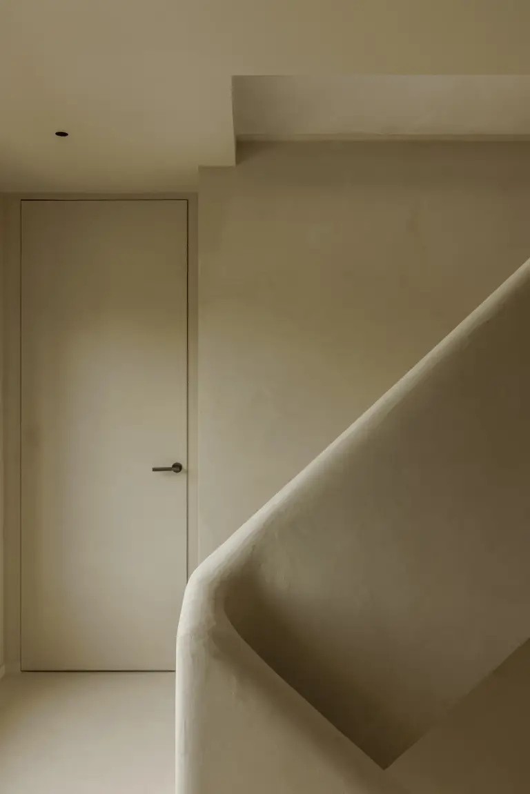 Trappenhuis met gepleisterde trap en vlakke deur, Villarenovatie in Knokke, interieur Laura Calleeuw