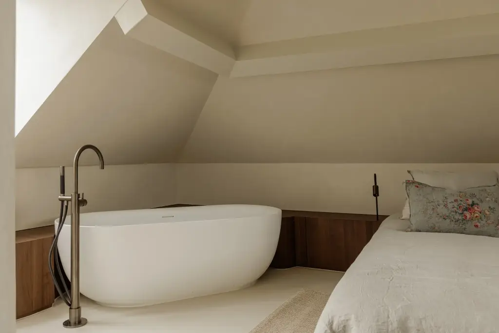 Vrijstaand bad met vrijstaande badkraan en omkasting in notelaar onder de dakhelling, Villarenovatie in Knokke, interieur Laura Calleeuw