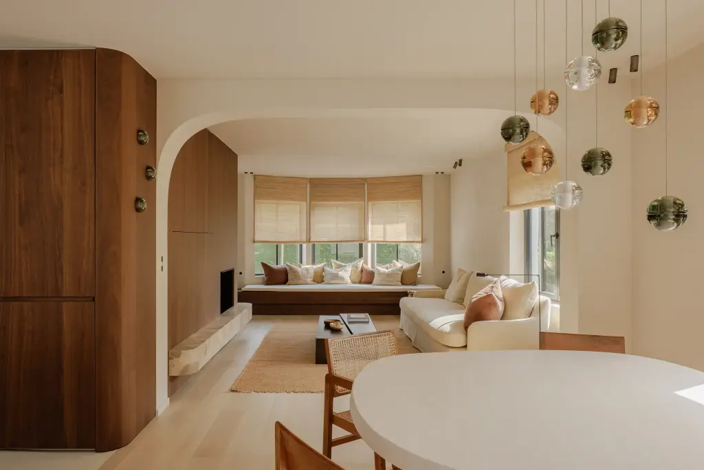 Leefruimte met kleurrijke glazen hanglampen boven de eettafel en een notelaren kastenwand, Villarenovatie in Knokke, interieur Laura Calleeuw