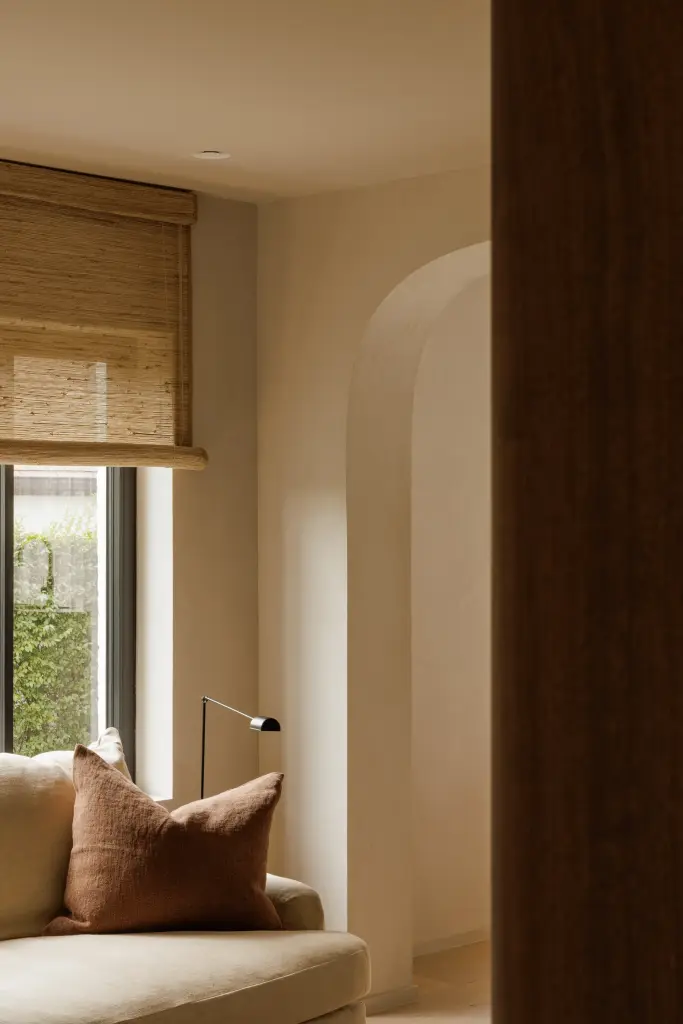 Zithoek met een kussen, boogopening en een raam met roman blind, Villarenovatie in Knokke, interieur Laura Calleeuw