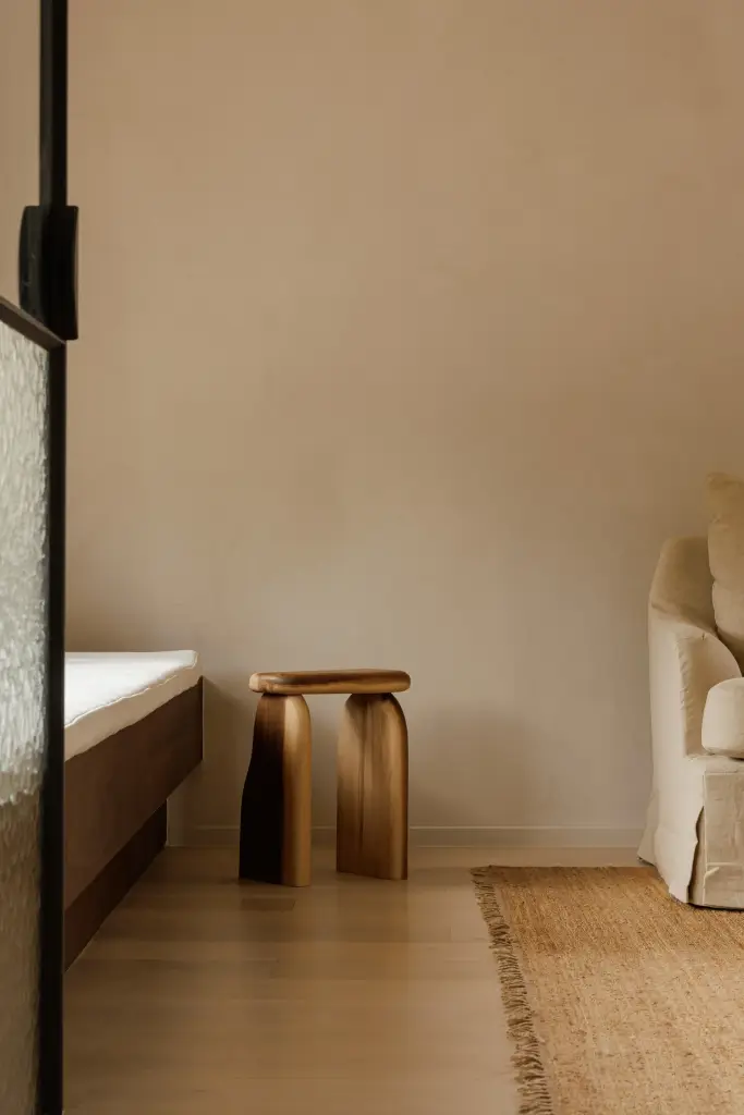 Zitkamer achter een stalen glaswand met fauteuil, bijzettafeltje en een jute tapijt, Villarenovatie in Knokke, interieur Laura Calleeuw
