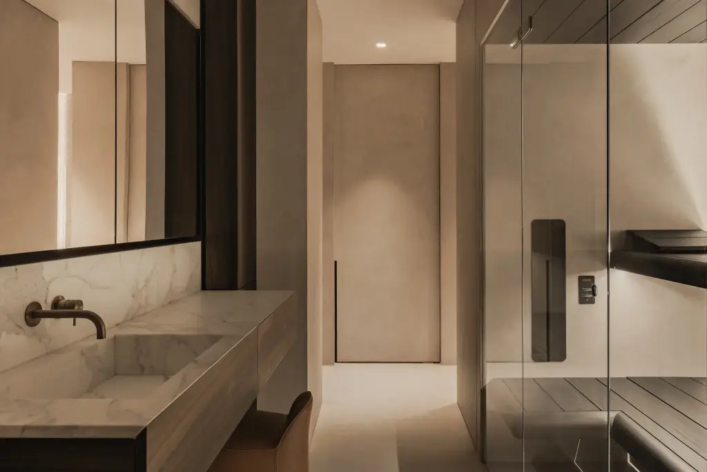 Marmeren wastafel met wandkraan, glaswand naar de sauna en doorkijk naar de slaapkamer, Penthouse in Kortrijk, interieur Laura Calleeuw
