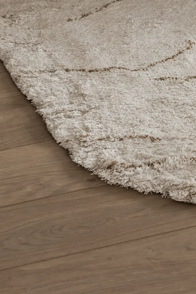 Detail van een beige wollen tapijt op eikenhouten parket, Penthouse in Kortrijk, interieur Laura Calleeuw