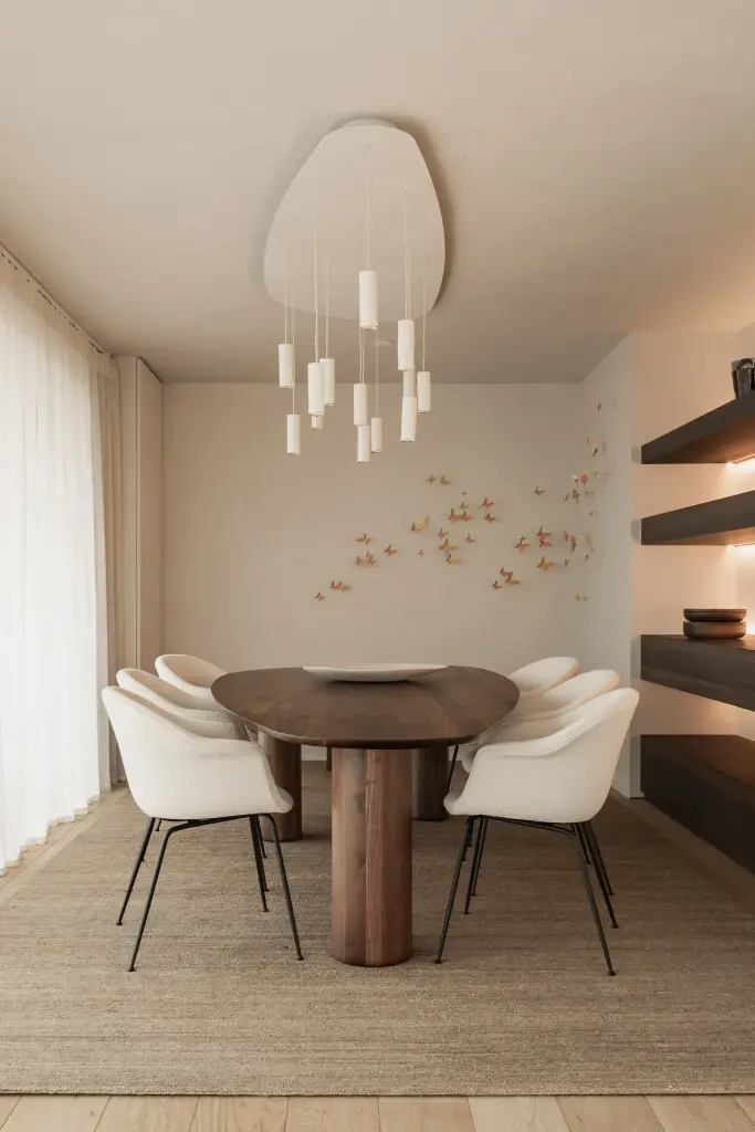 Eetkamer met ovale tafel, witte stoelen, hanglamp en een wand met gouden vlinders, Penthouse in Kortrijk, interieur Laura Calleeuw
