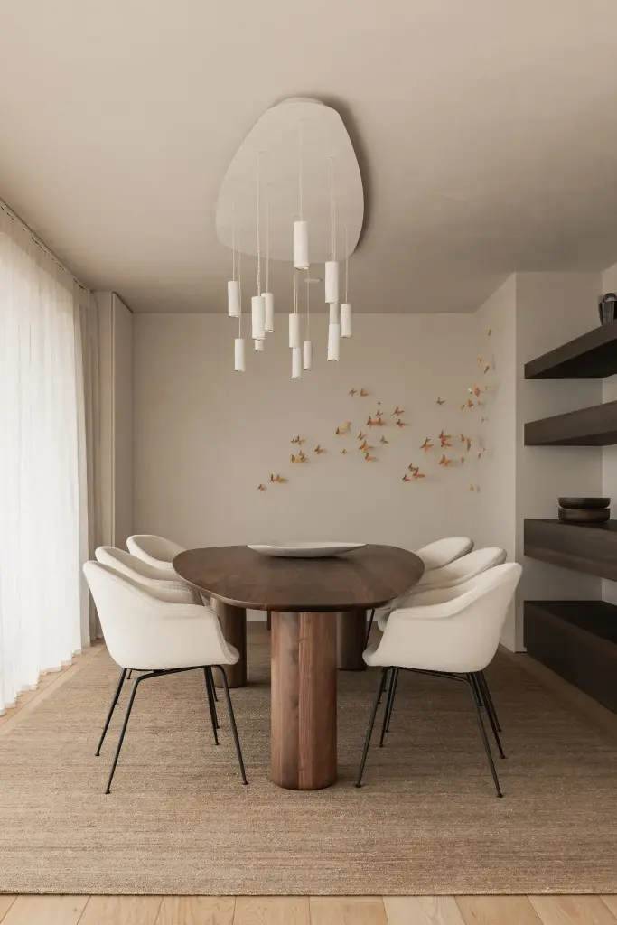 Eetkamer met ovale tafel, witte stoelen, hanglamp en een wand met gouden vlinders, Penthouse in Kortrijk, interieur Laura Calleeuw