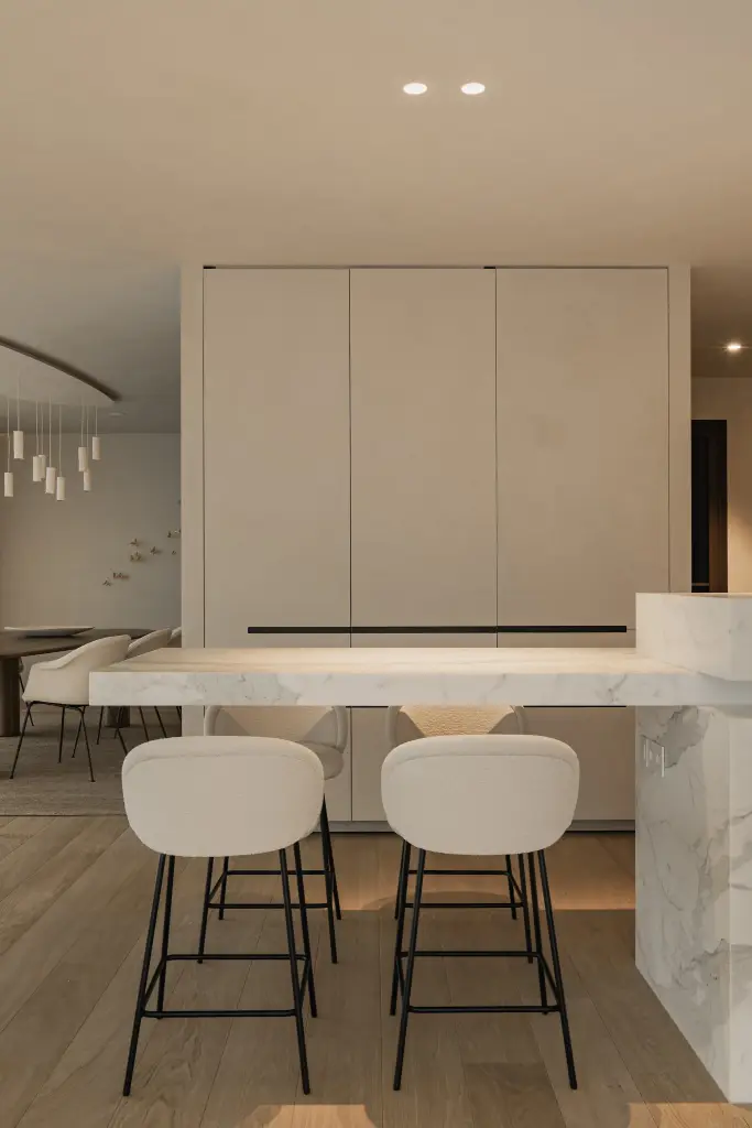Keuken met witte kastenwand en inbouwoven, kookeiland in marmer met barkrukken, Penthouse in Kortrijk, interieur Laura Calleeuw