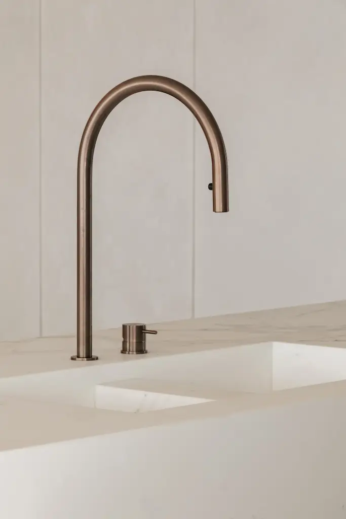 Keukenkraan in koper boven een witte spoelbak, Penthouse in Kortrijk, interieur Laura Calleeuw