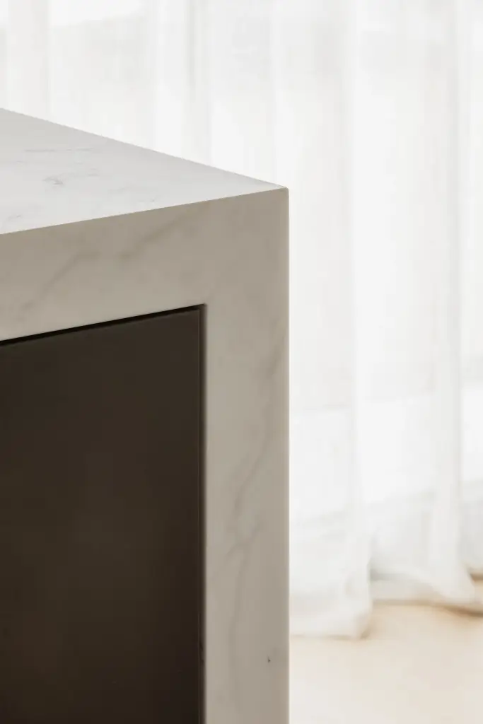 Hoek van het marmeren kookeiland naast een gordijn, Penthouse in Kortrijk, interieur Laura Calleeuw