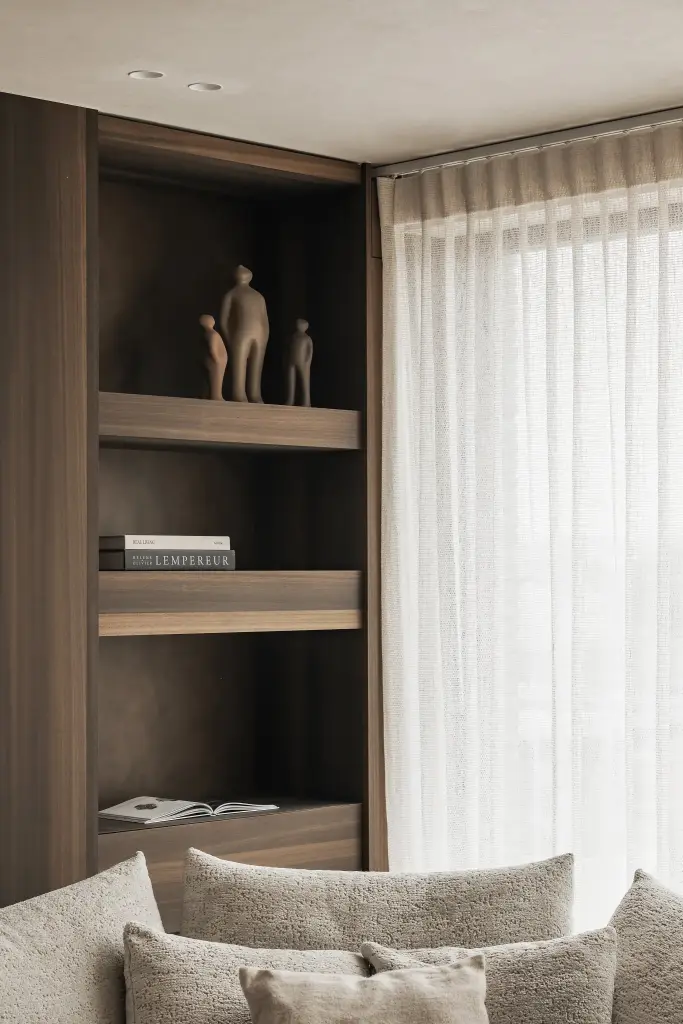 Nis in notelaar met planken, beeldjes en een gordijn naast de sofa, Penthouse in Kortrijk, interieur Laura Calleeuw