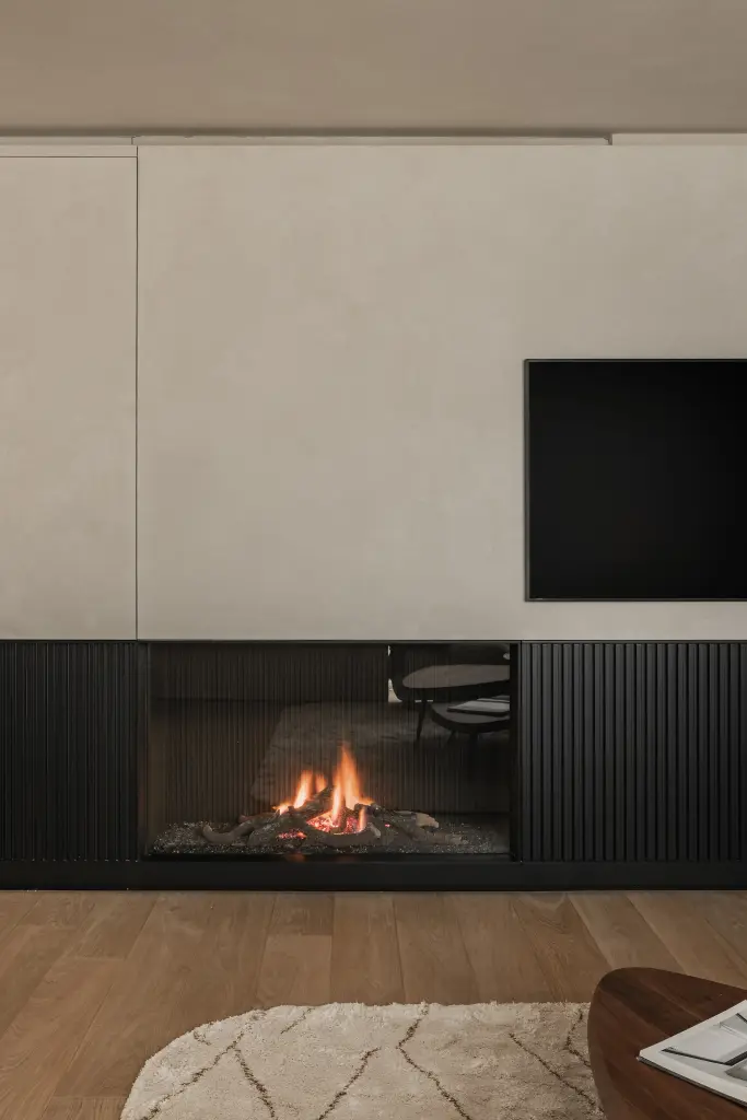 Open haard in een zwarte lamellenwand onder een televisie in een gepleisterd paneel, Penthouse in Kortrijk, interieur Laura Calleeuw