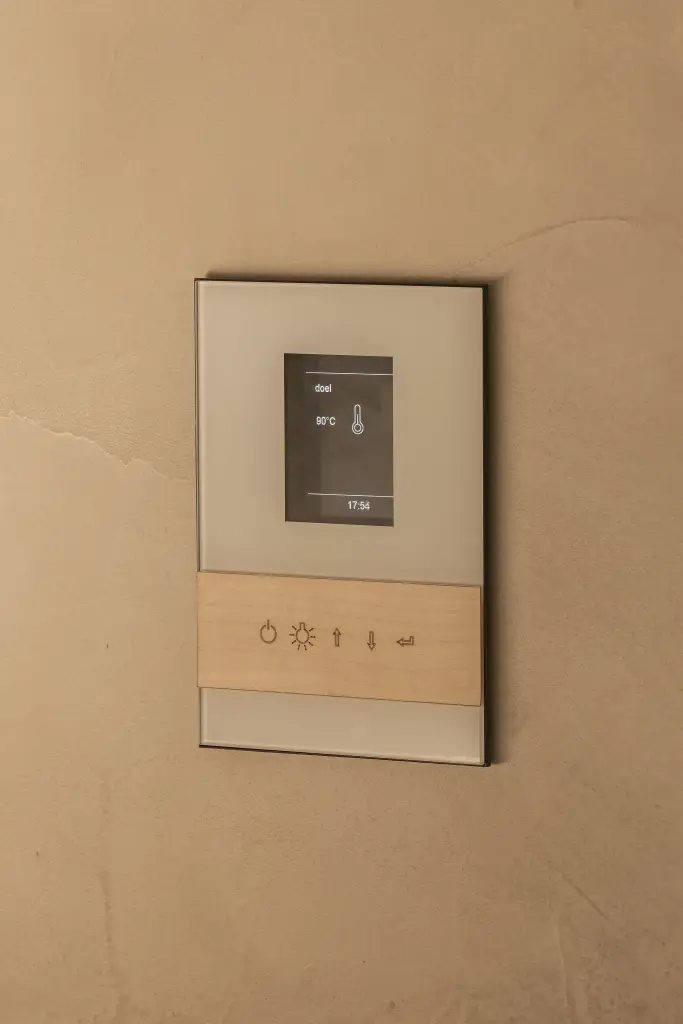 Bedieningspaneel van de sauna met houten afwerking op een gepleisterde wand, Penthouse in Kortrijk, interieur Laura Calleeuw
