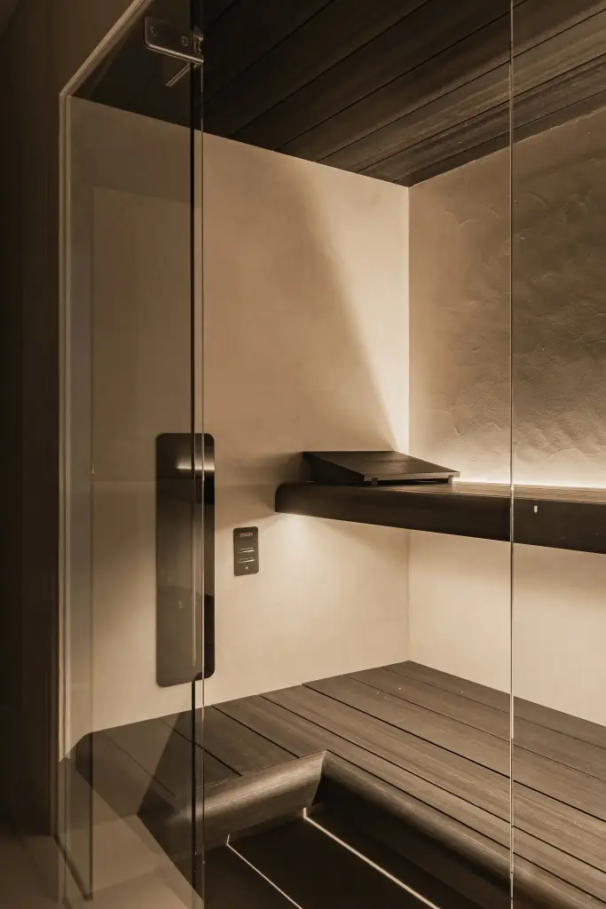Sauna met houten bank, glazen deur, zwarte verwarmingspaneel en indirecte verlichting, Penthouse in Kortrijk, interieur Laura Calleeuw