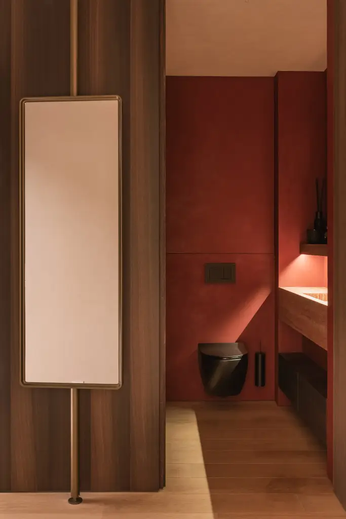 Toilet met rode pleisterwand, notelaren wand en een zwart hangtoilet, Penthouse in Kortrijk, interieur Laura Calleeuw