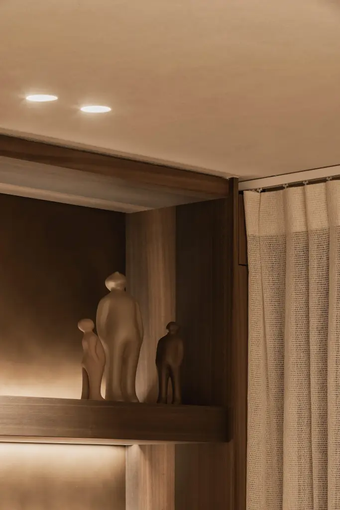 Verlichte nis in notelaar met beeldjes en een zacht gordijn, Penthouse in Kortrijk, interieur Laura Calleeuw