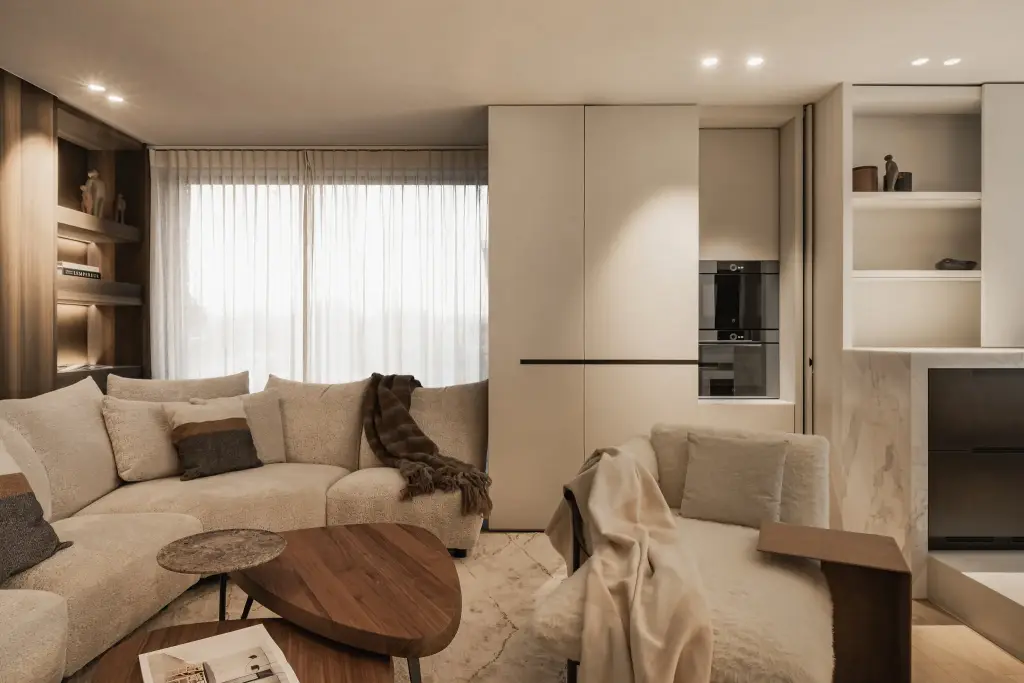 Hoeksofa met plaid, salontafel in notelaar en een raam met vitrage, Penthouse in Kortrijk, interieur Laura Calleeuw