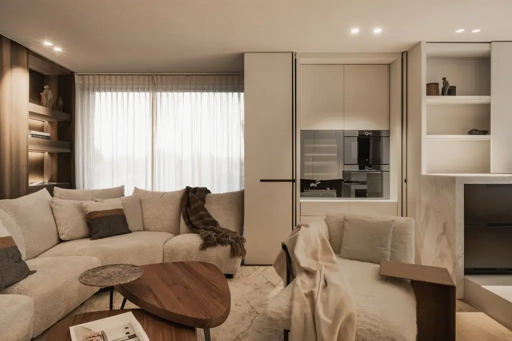 Hoeksofa met plaid, salontafel in notelaar en een raam met vitrage, Penthouse in Kortrijk, interieur Laura Calleeuw