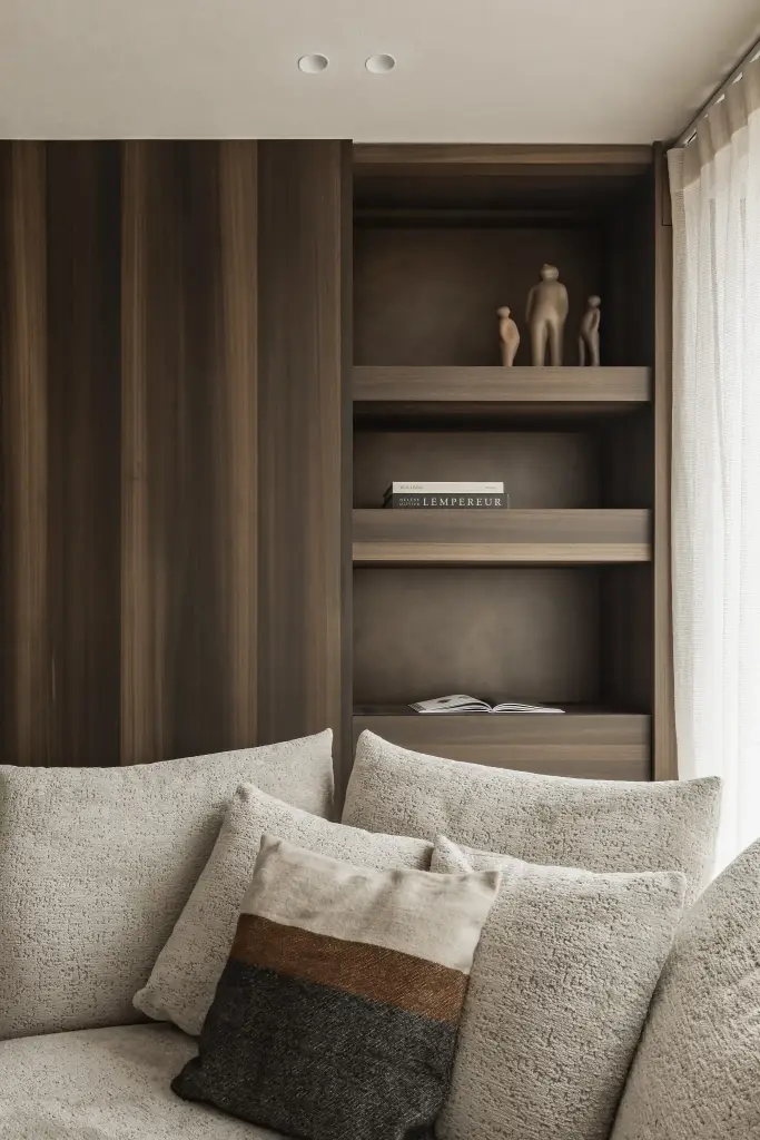 Sofa met kussens voor een notelaren kast met indirect licht, Penthouse in Kortrijk, interieur Laura Calleeuw