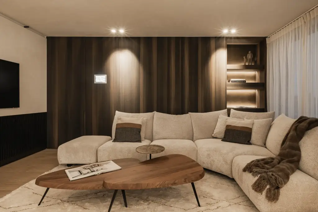 Hoeksofa, organische salontafel in notelaar en plaid voor een notelaren wand, Penthouse in Kortrijk, interieur Laura Calleeuw