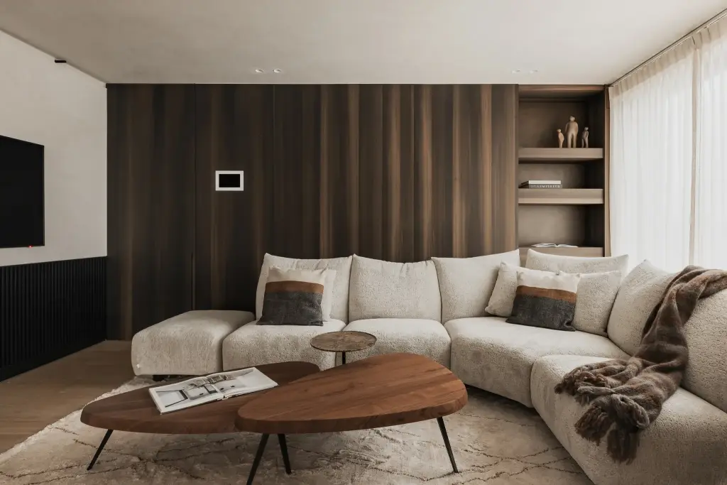 Hoeksofa, organische salontafel in notelaar en plaid voor een notelaren wand, Penthouse in Kortrijk, interieur Laura Calleeuw