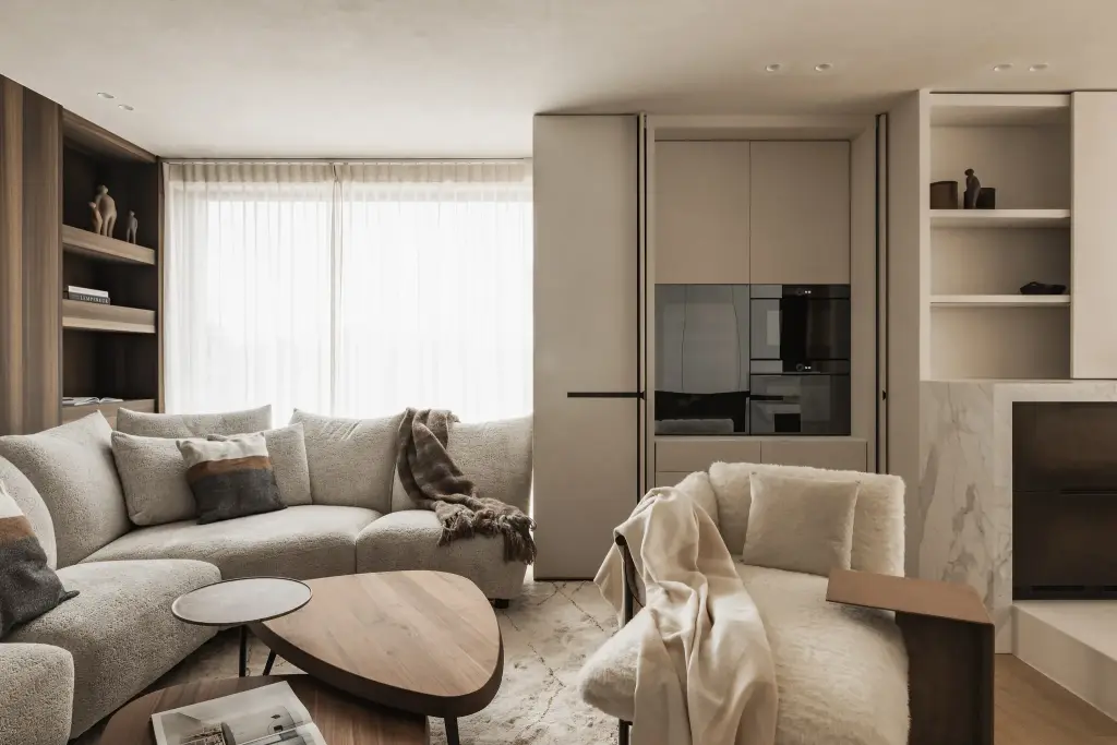 Zithoek met hoeksofa, notelaren salontafel en fauteuil voor een kastenwand met verborgen inbouwoven, Penthouse in Kortrijk, interieur Laura Calleeuw