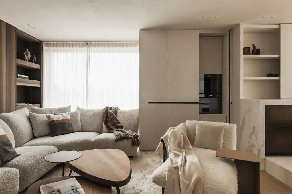 Zithoek met hoeksofa, notelaren salontafel en fauteuil voor een kastenwand met verborgen inbouwoven, Penthouse in Kortrijk, interieur Laura Calleeuw