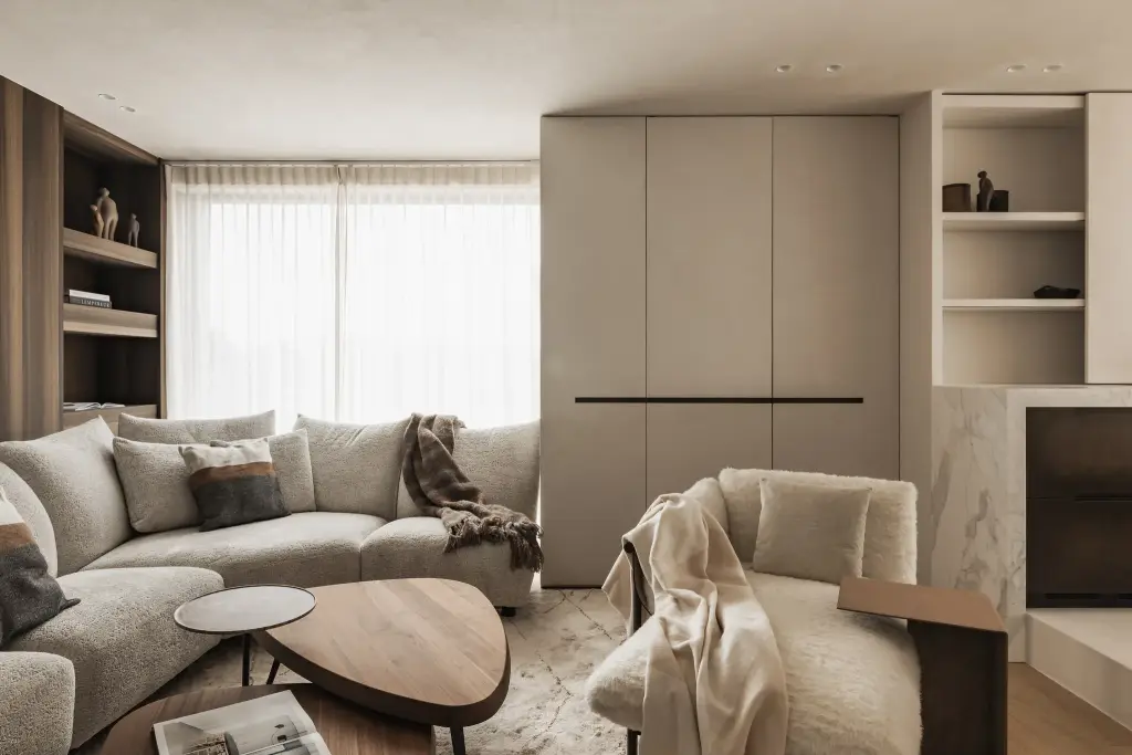Zithoek met hoeksofa, notelaren salontafel en fauteuil voor een kastenwand met verborgen inbouwoven, Penthouse in Kortrijk, interieur Laura Calleeuw
