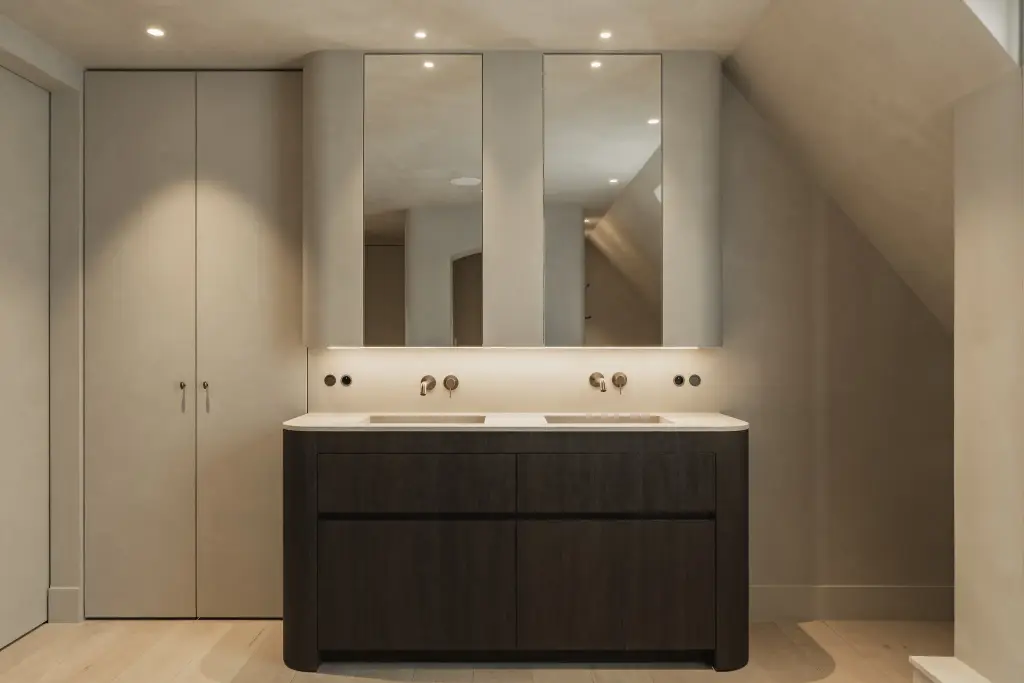 Dubbele wastafel op een donker eiken meubel onder spiegelkasten met indirect licht, Hoeve in Hansbeke, interieur Laura Calleeuw