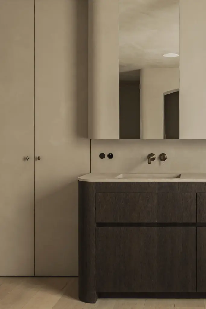 Badkamer met wastafelmeubel in donker eiken, wandkranen en een spiegelkast onder de dakhelling, Hoeve in Hansbeke, interieur Laura Calleeuw