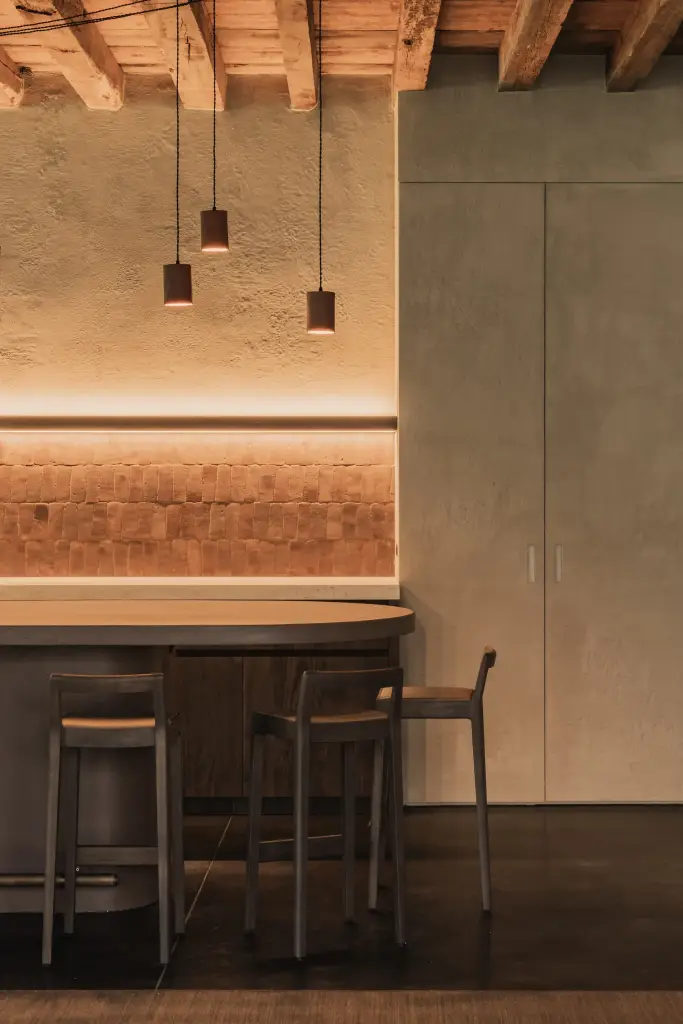 Terracotta hanglampen boven de bar met tegelwerk en barkrukken, Hoeve in Hansbeke, interieur Laura Calleeuw