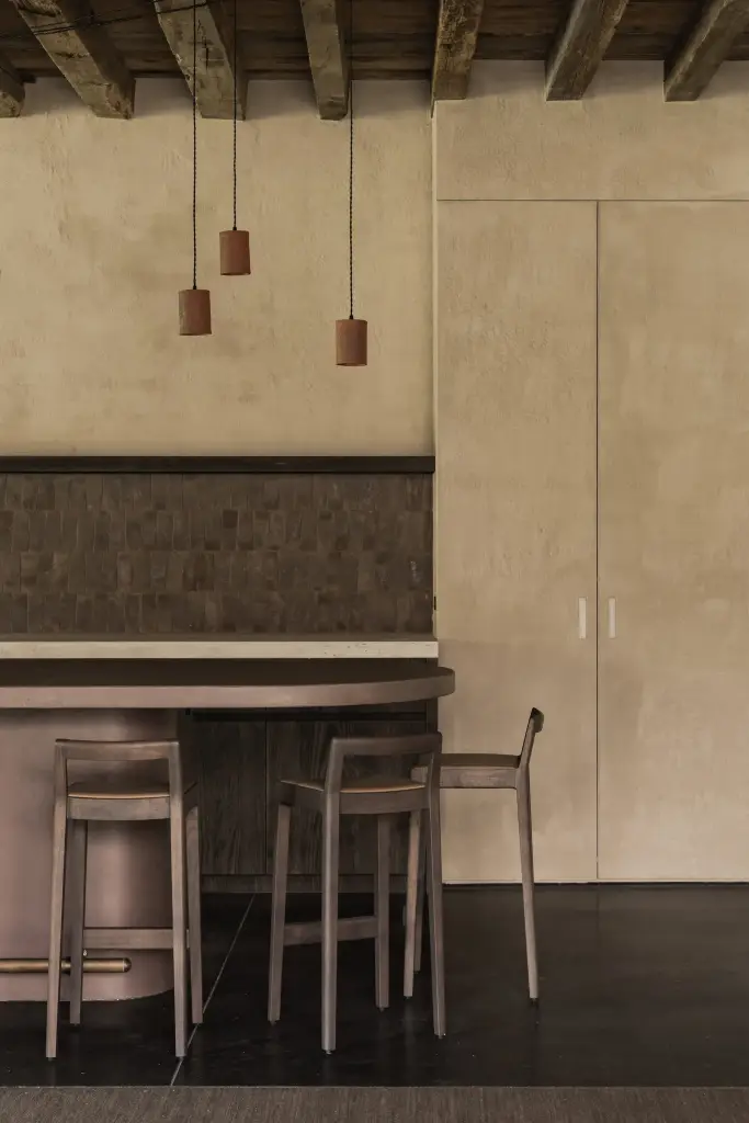 Terracotta hanglampen boven de bar met tegelwerk en barkrukken, Hoeve in Hansbeke, interieur Laura Calleeuw