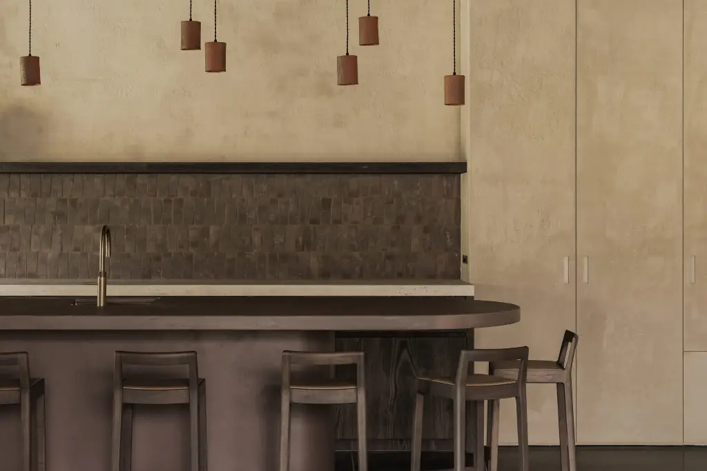 Terracotta hanglampen en tegelwand met ledlijn boven het kookeiland met kraan, Hoeve in Hansbeke, interieur Laura Calleeuw