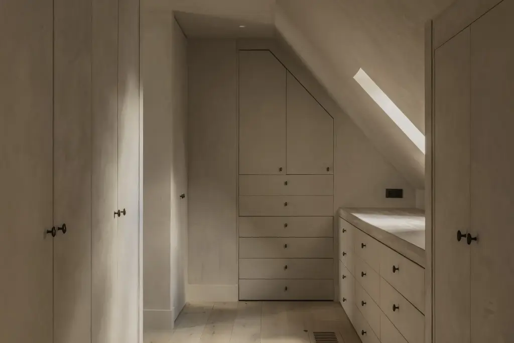 Dressing onder de dakhelling met kastdeuren in kalkpleister, een ladekast en een dakraam, Hoeve in Hansbeke, interieur Laura Calleeuw
