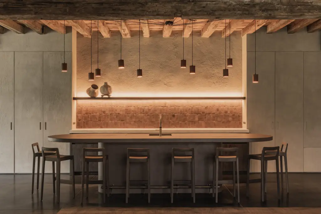 Eetbar met ovaal kookeiland, barkrukken, terracotta hanglampen en oude houten balken, Hoeve in Hansbeke, interieur Laura Calleeuw