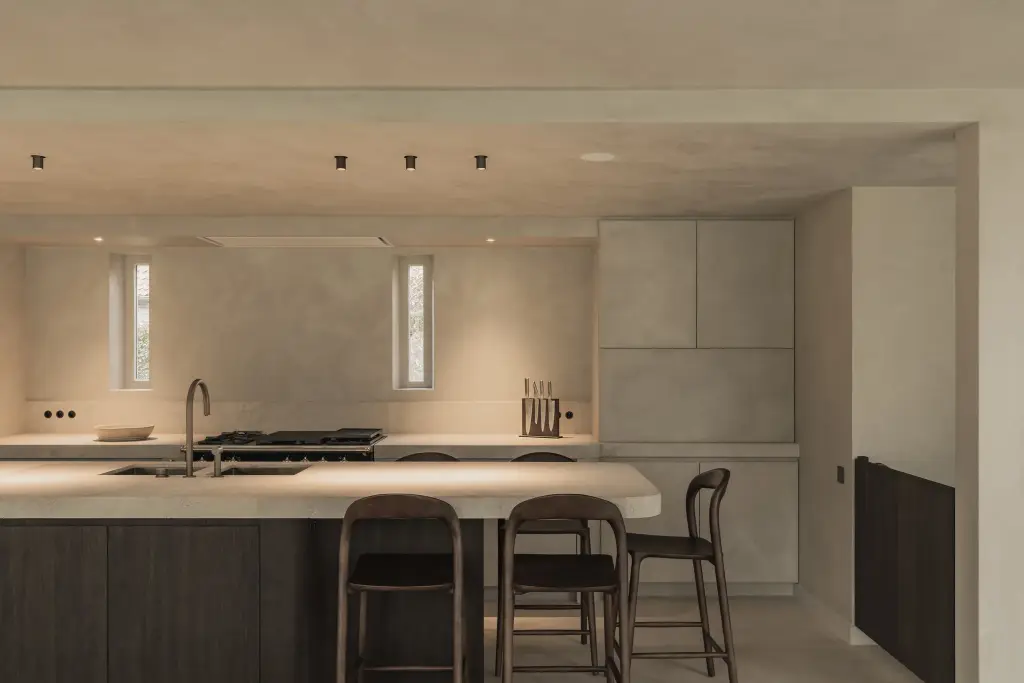 Keuken met fornuis, eiland met natuurstenen blad, barkrukken en een smal raam, Hoeve in Hansbeke, interieur Laura Calleeuw