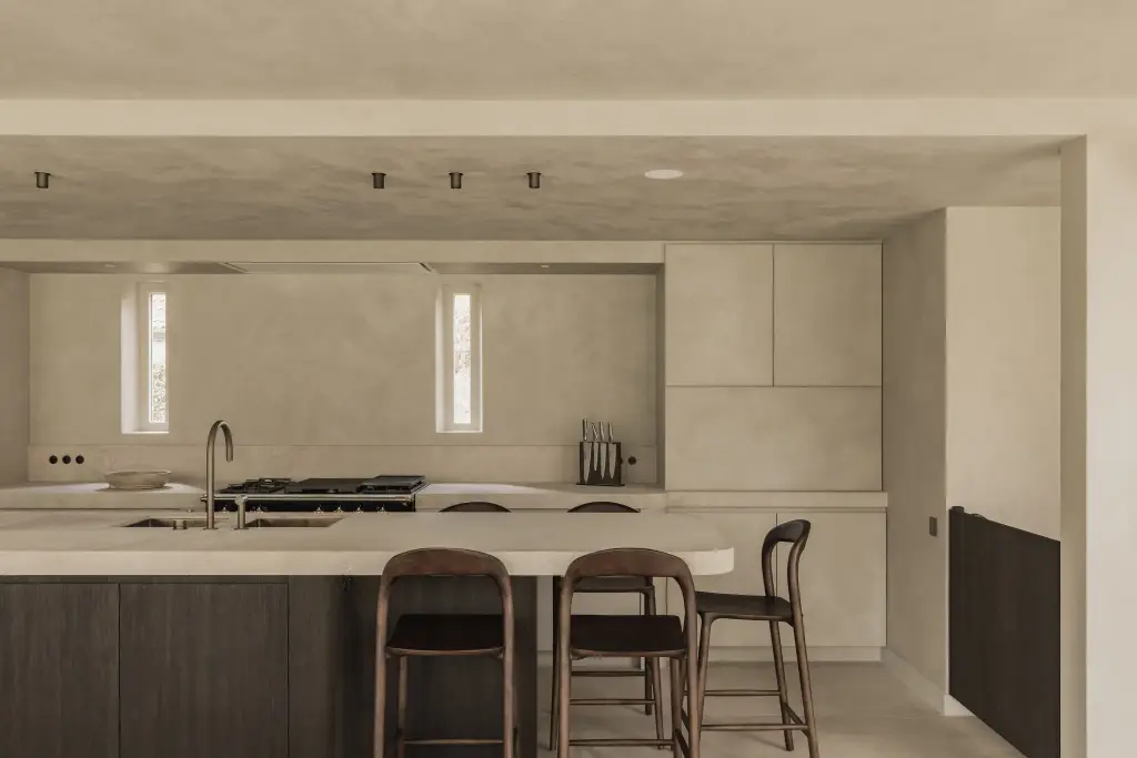 Keuken met fornuis, eiland met natuurstenen blad, barkrukken en een smal raam, Hoeve in Hansbeke, interieur Laura Calleeuw