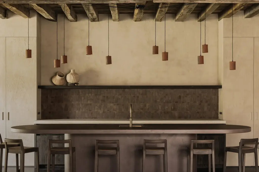 Keukenbar met verlichte terracotta tegelwand, plank met vazen en ovaal kookeiland, Hoeve in Hansbeke, interieur Laura Calleeuw