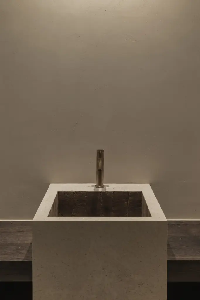 Natuurstenen wastafelzuil met koperen kraan en een spoelbak in terracotta tegels, Hoeve in Hansbeke, interieur Laura Calleeuw