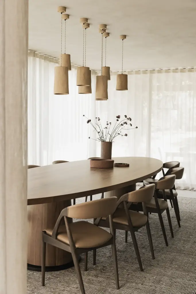 Ovale eettafel met leren stoelen, droogbloemen en hanglampen in aardewerk, Hoeve in Hansbeke, interieur Laura Calleeuw