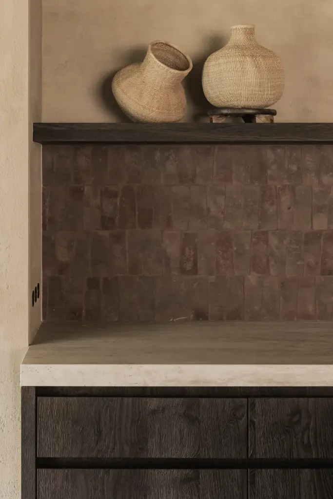 Plank met aarden vazen voor een verlichte terracotta tegelwand, Hoeve in Hansbeke, interieur Laura Calleeuw