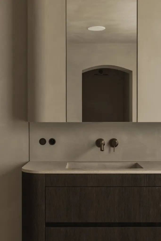 Wastafel met wandkraan en een spiegel met boogvormige nis boven donker eiken onderkast, Hoeve in Hansbeke, interieur Laura Calleeuw