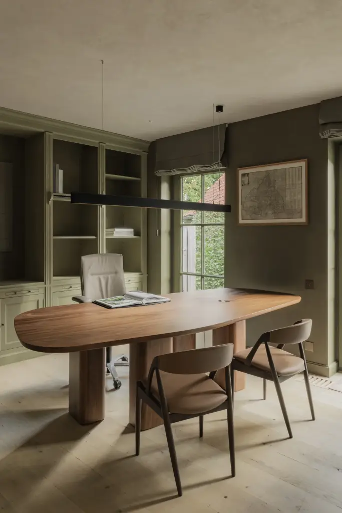 Werkkamer met ovale tafel, leren stoelen, lange hanglamp en groene kastenwand, Hoeve in Hansbeke, interieur Laura Calleeuw