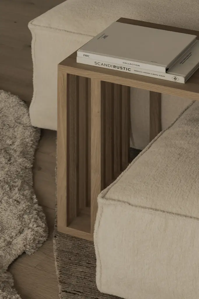 Houten zijtafel met boeken naast de sofa en een vachtkleed, Hoeve in Hansbeke, interieur Laura Calleeuw