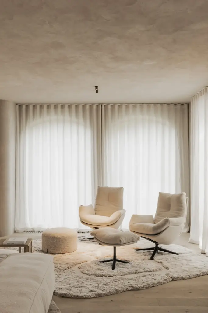 Zithoek met twee draaifauteuils, een poef en een vachtkleed voor hoge vensters, Hoeve in Hansbeke, interieur Laura Calleeuw
