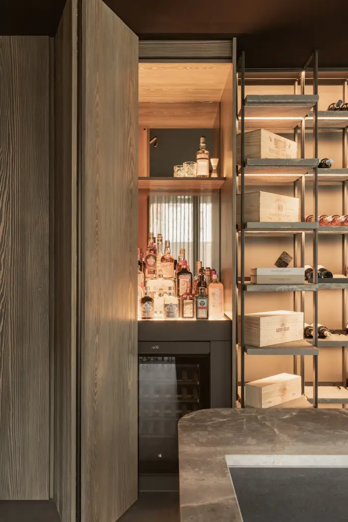 Open barkast met flessen en een wijnkoeler onder indirecte verlichting, a space that changes with the rhythm of the day, interieur Laura Calleeuw