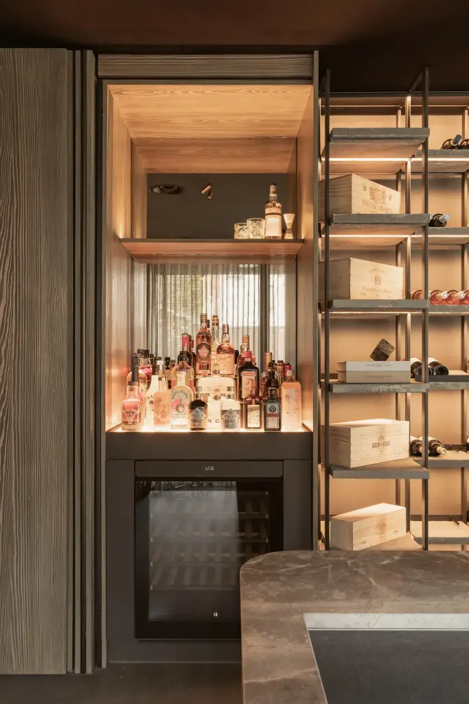 Open barkast met flessen en een wijnkoeler onder indirecte verlichting, a space that changes with the rhythm of the day, interieur Laura Calleeuw